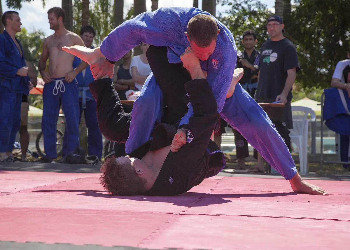 A grappler on his back controls a standing opponent from guard