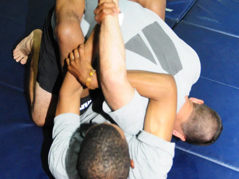 A grappler on his back attacking a kimura from closed guard with a figure-four grip
