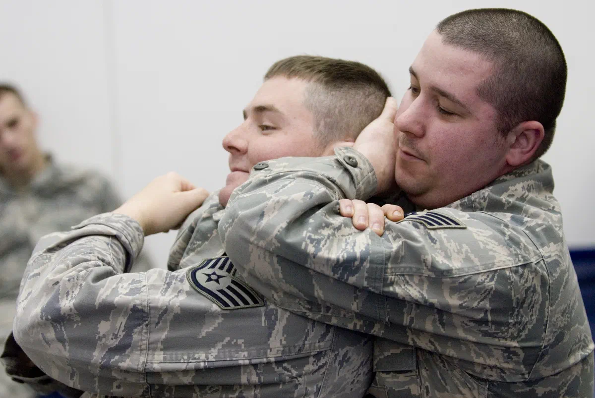 A rear naked choke applied from behind, one arm under the chin and the other hand behind the head